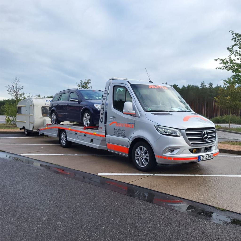 PKW auf Abschleppfahrzeug und Wohnwagen angehängt